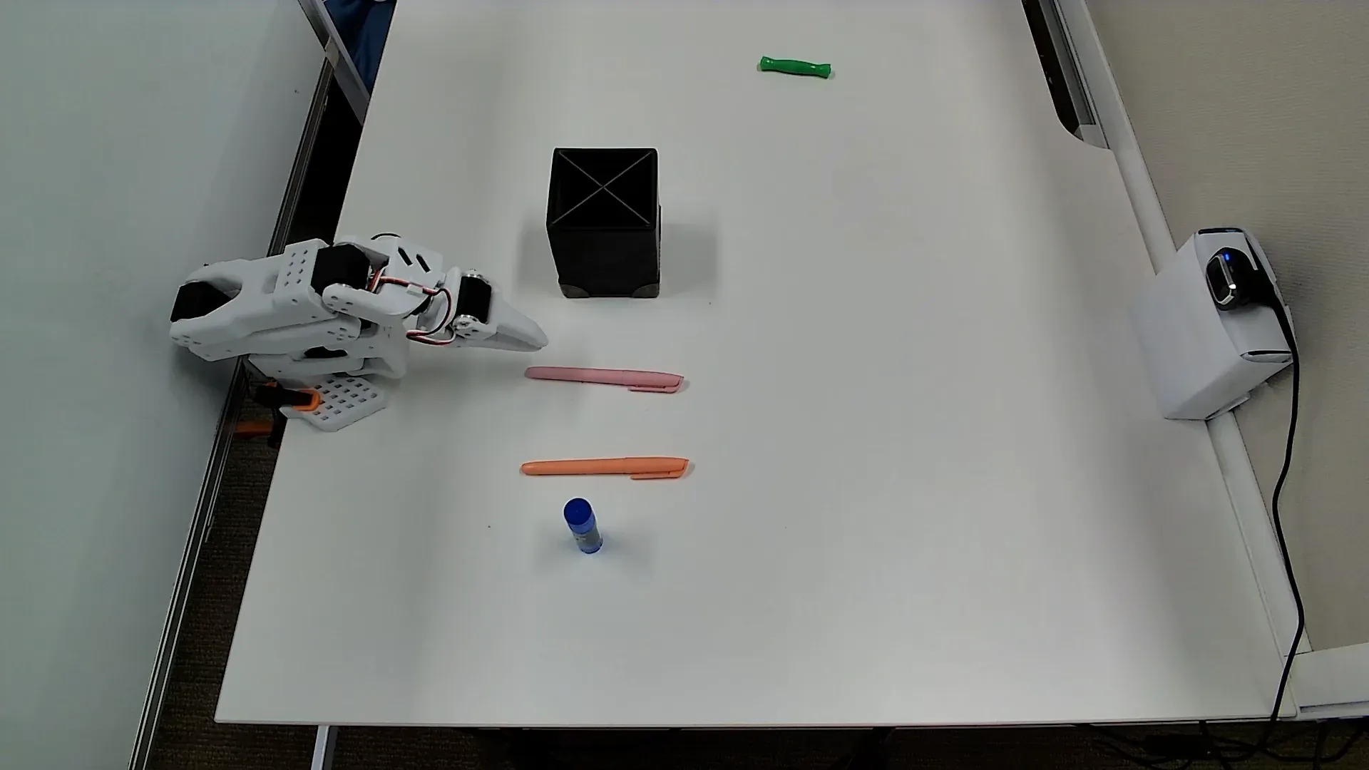 Top camera view of the Bus Table (Easy) workspace with pens and glue stick around the holder.